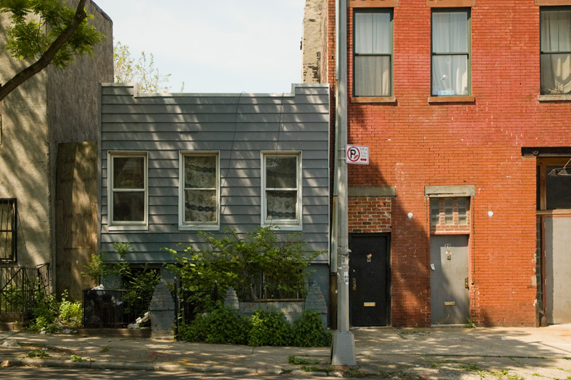 A house, right next to a brick industrial building.