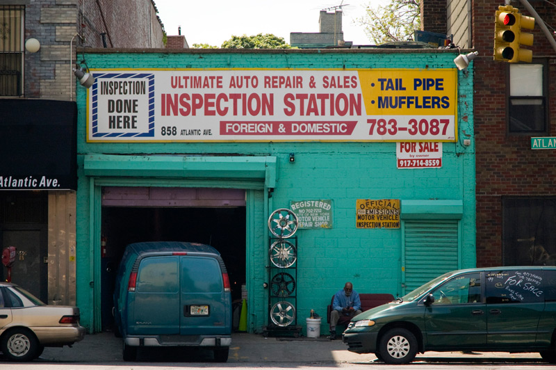 Vans and a man sit outside an auto shop, painted turquoise.