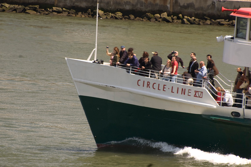 Tourists in the bow of a boat enjoy skyline views.