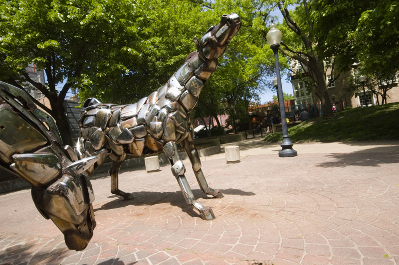 Two chrome horse statues, in a park plaza.