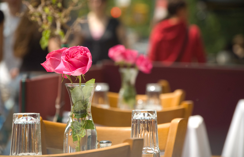 Pink roses and sidewalk tables await diners.