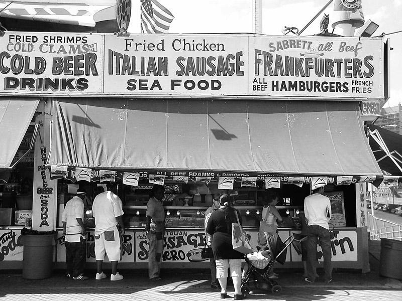 A canopied fast food counter with people lined up to buy.