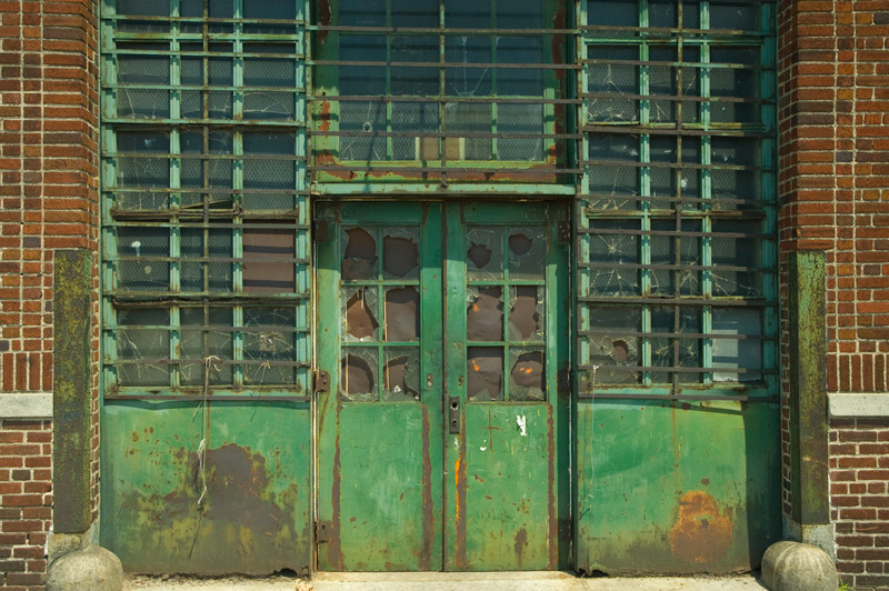 Green metal double doors, with broken panes of glass.