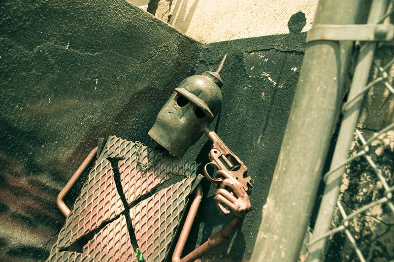 A knight, sculpted from bent pipes, holding a gun to his head.