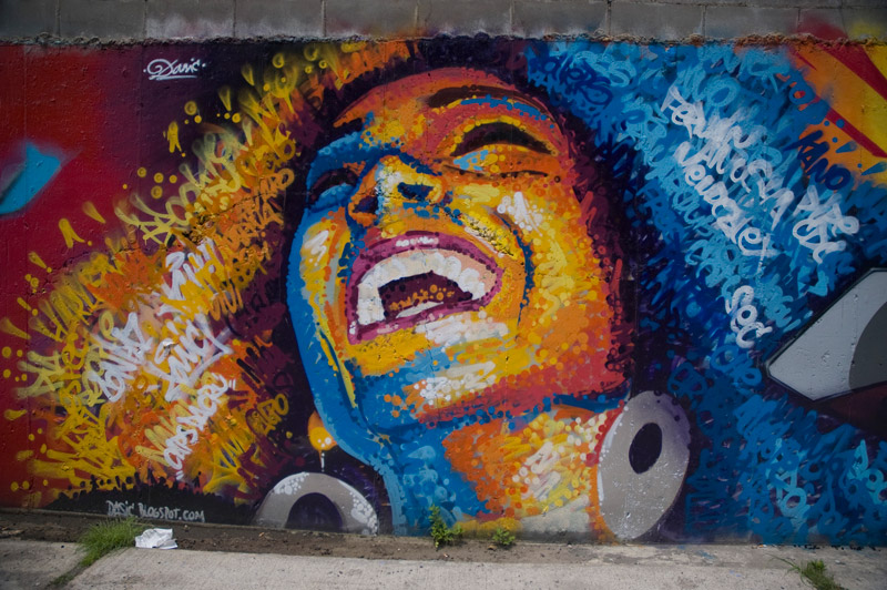 A mural of a woman's face, happy, in brilliant colors.