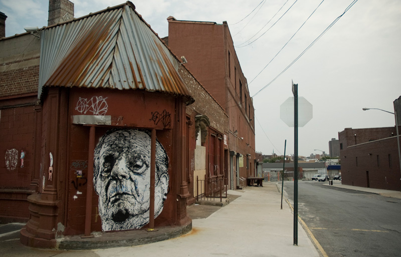 An abandoned building's entrance is now covered with a poster of a face.