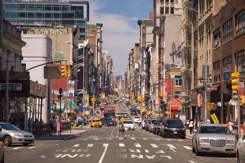 A man crosses Broadway, with many blocks' worth of traffic.