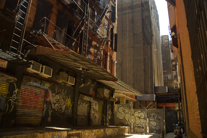 Light shines into a canyon of loading docks and graffiti.