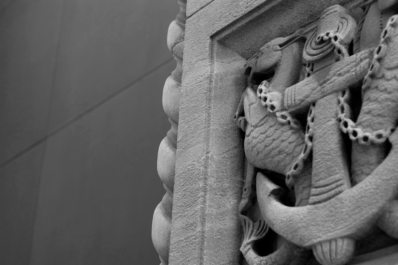 Sea horses and anchors sculpted on the side of a building.