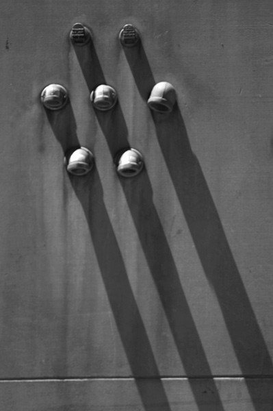Protruding pipes cast shadows on the wall and each other.