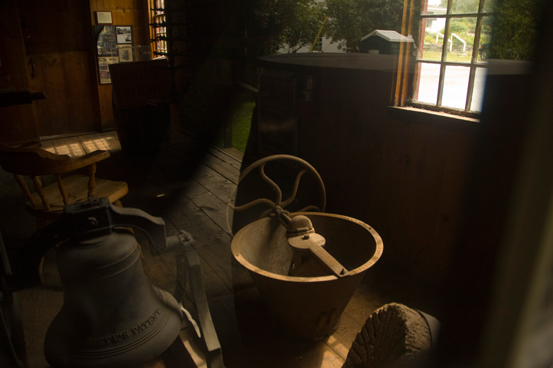 Milling machinery sits in a sunbeam on a wooden floor.