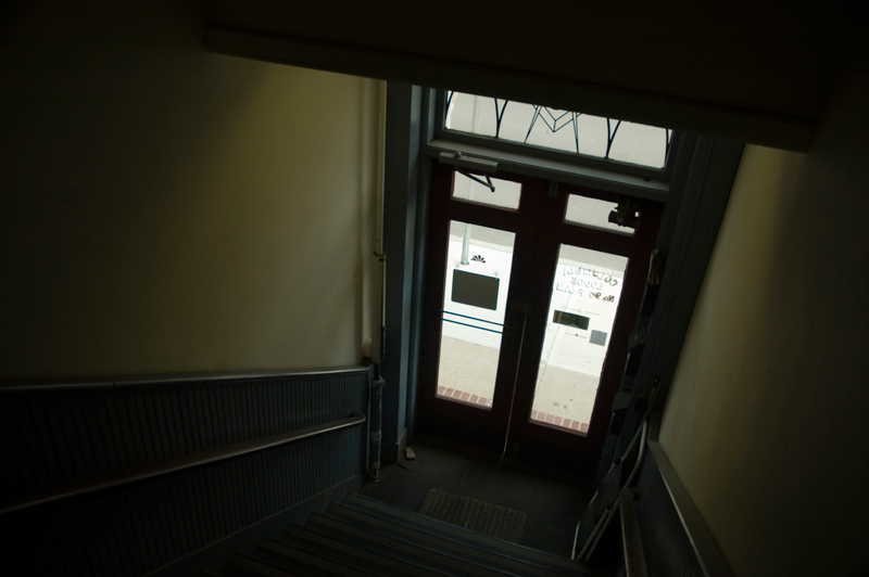 Darkened stairs leading to glass doors and the street.