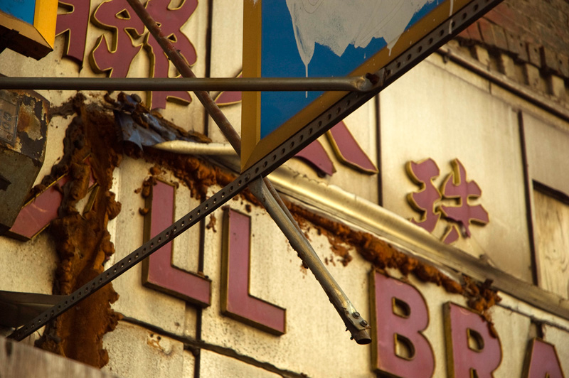 An old sign in Chinese characters, with dirt and leaking sealant.