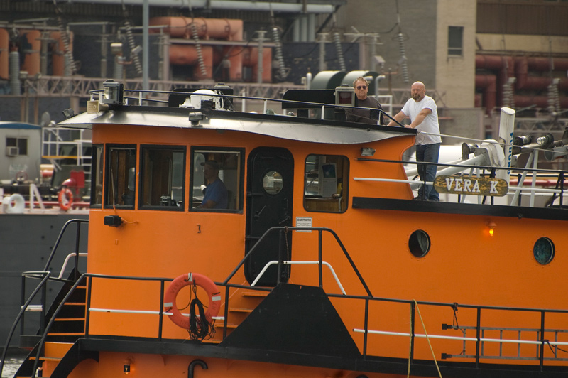 A crew, on an orange tugboat's bridge.