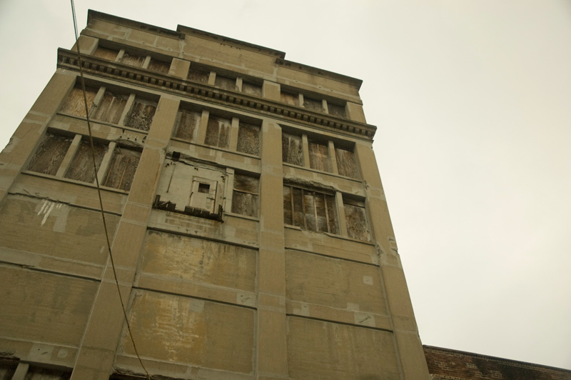 A tall dingy building with boarded-up windows.