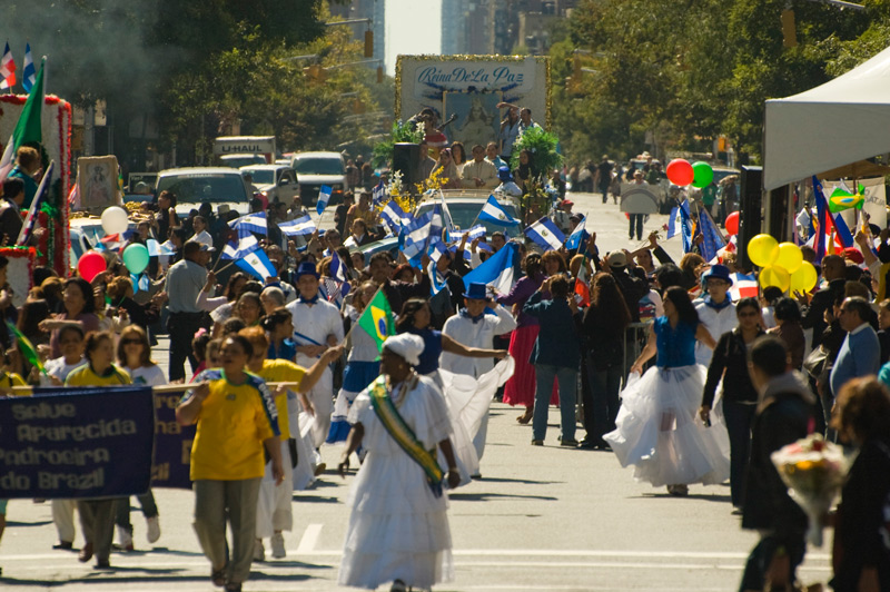 A relgious parade float and its followers, in Brazilian colors, on an avenue.