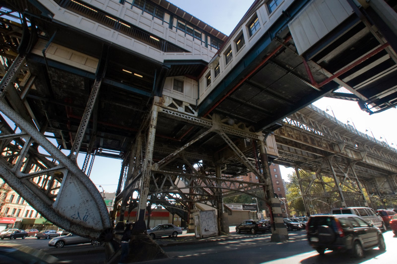 An intricate subway overpass: stairs, elevated walkways, and trellises, all made of metal.