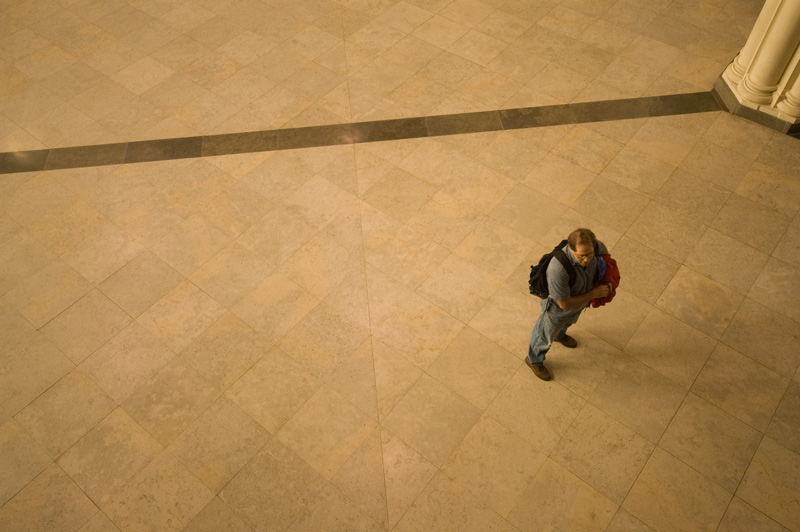 A lone figure, seen below from a balcony.