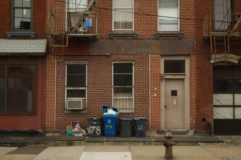 A red brick home, trashcans out front.