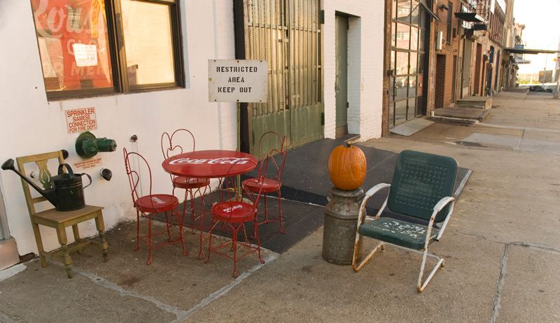 A sign in front of a store says 'Keep Out,' in spite of patio chairs and a table.