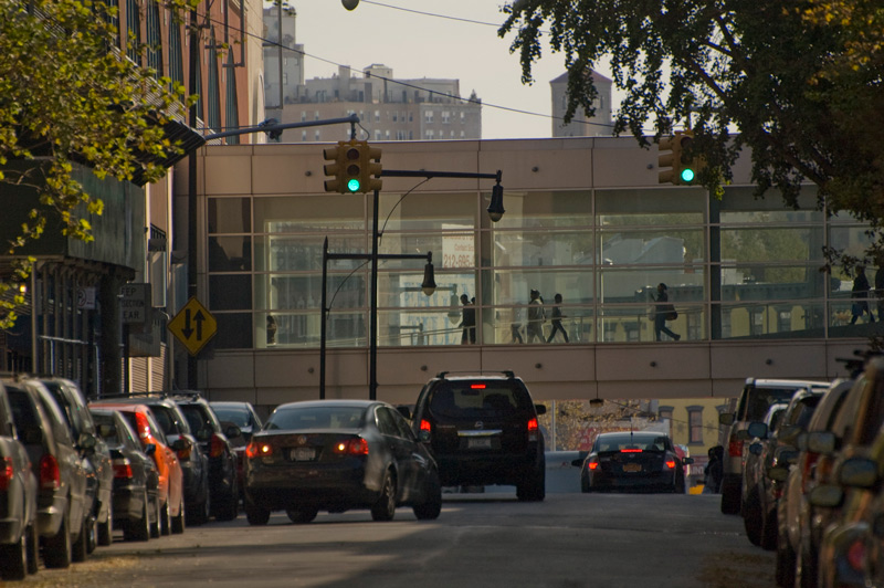 Cars head to a glass-windowed pedestrian walkway.