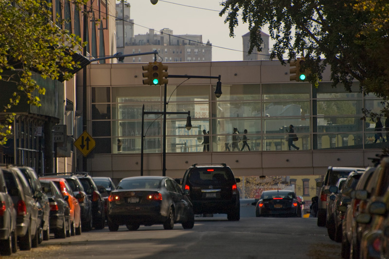Cars head to a glass-windowed pedestrian walkway.