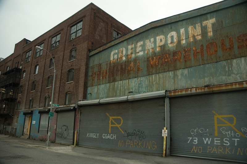 An old building of corrugated metal, painted green, with rust streaks.