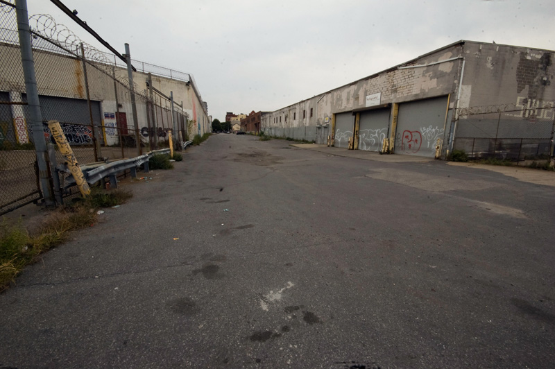 A bleak street, with low industrial buildings on each side.
