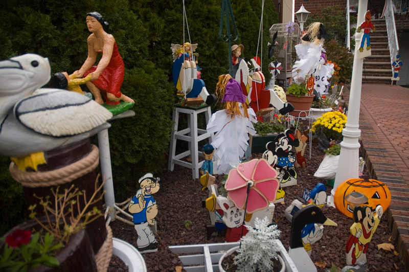 A front lawn, decorated with an assortment of figures such as Popeye, Mickey Mouse, pelicans, etc.