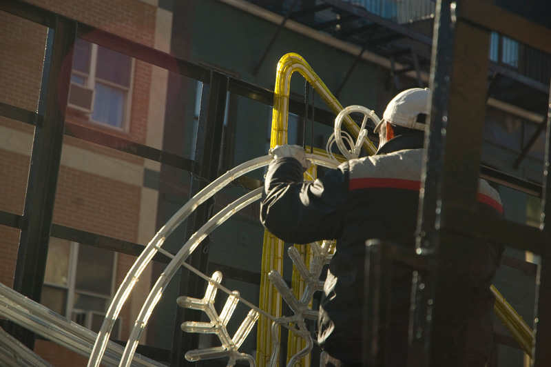 A man on a truck prepares a Christmas decoration for an intersection.