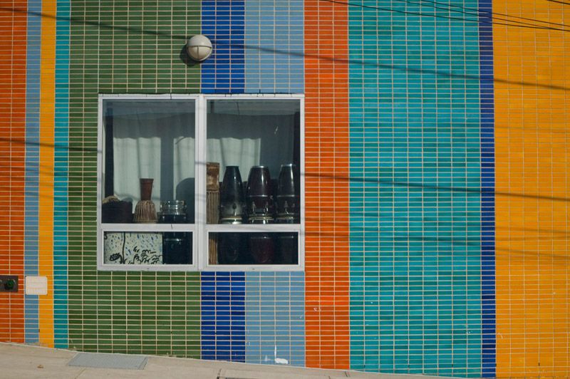 African and Latin drums in a window, on a multi-colred wall.