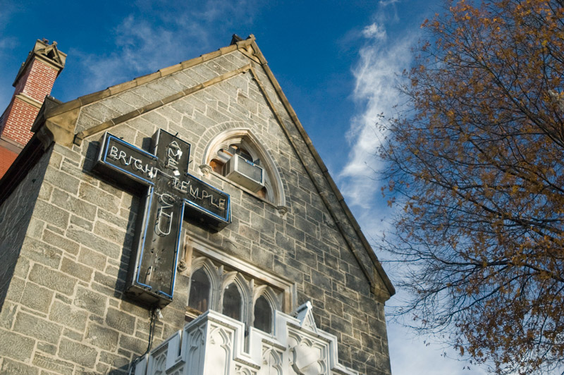 A church in a stone building; broken neon; blue sky.