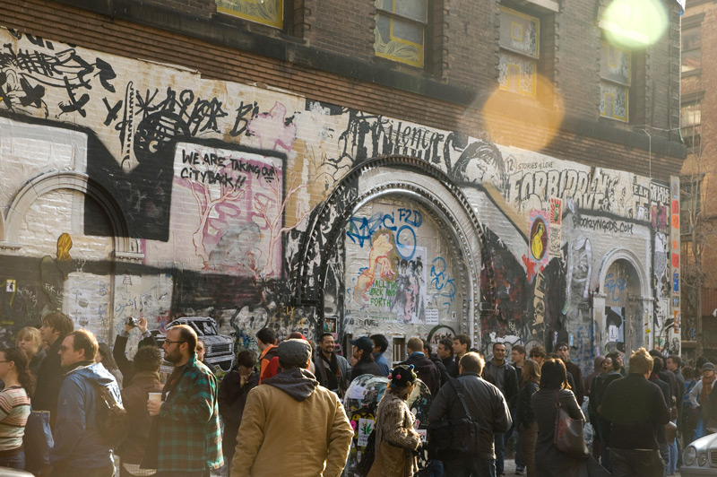 Young people cluster around a building given over to street art.