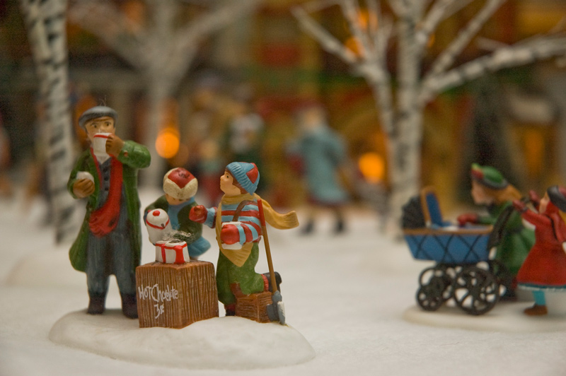 Small winter figurines of children selling cocoa to an adult.