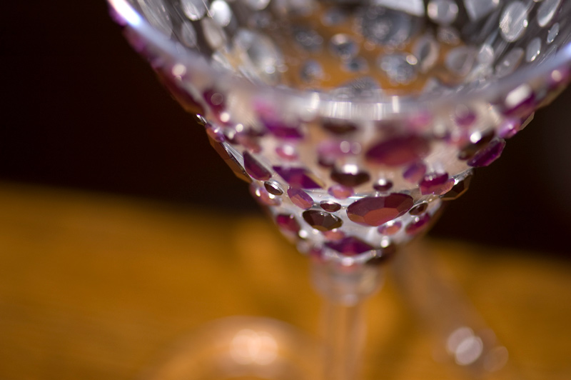 A plastic, stemmed champagne glass, with purple baubles.