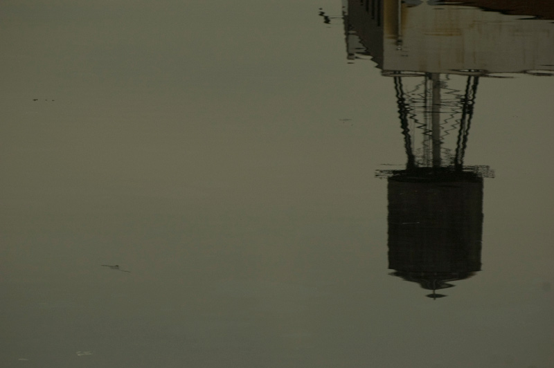 Ripples in water distort the reflection of a building water tank.