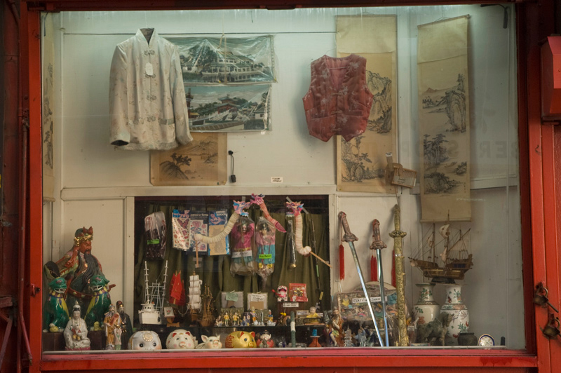 A window showcases swords, garments, and other Asian paraphenelia.