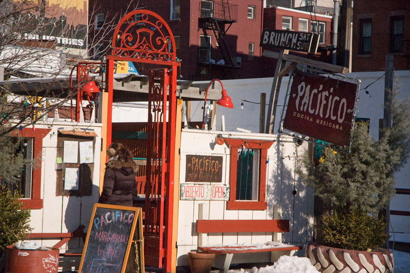 A passer-by reviews the menu at a Mexican restaurant, in red and white colors.