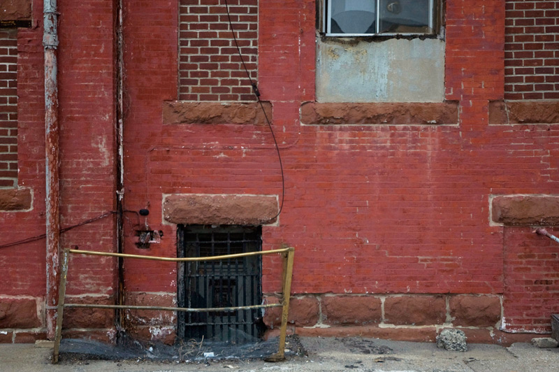 Brick building with bricked-in windows, and a basement window.