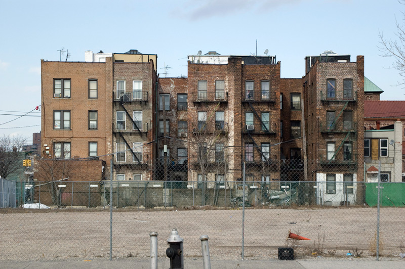 Apartment buildings, seen from the back of an empty lot.