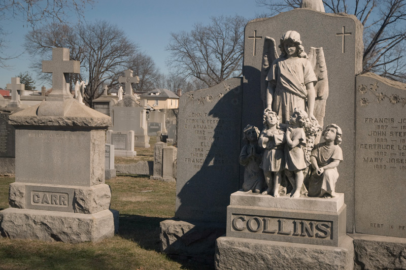 At a grave, a statue group of an angel and four children.