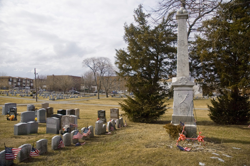 Military graves around an obelisk with U.S. Civil War reliefs.