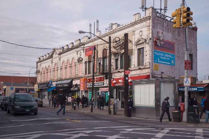 An Italianate building with stores on a city street.