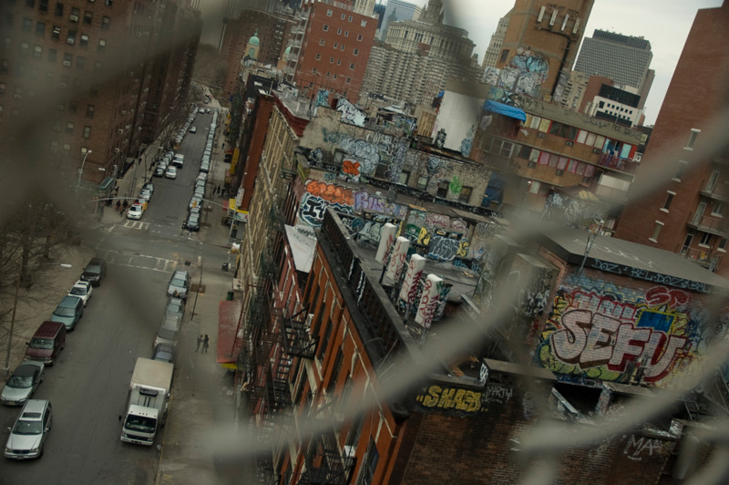 Graffiti on rooftops, seen through a fence