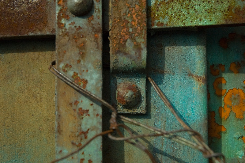 A bolt on an old metal fire door, painted in psychedelic colors.