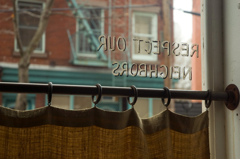 Painted gold leaf letters remind restaurant patrons to respect the neighbors.