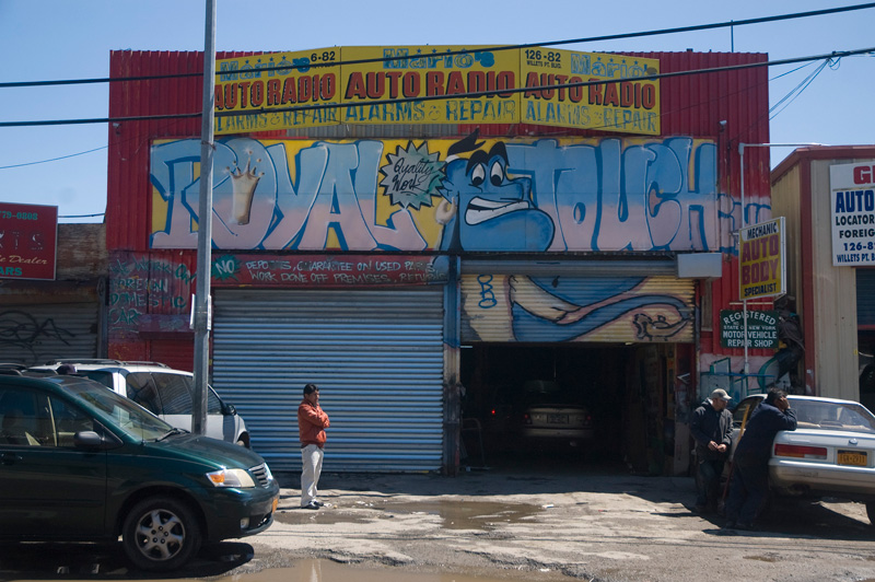 Men wait for business outside a brightly painted auto shop.