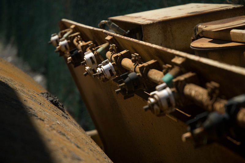 A row of water jets on a grimy steamroller.