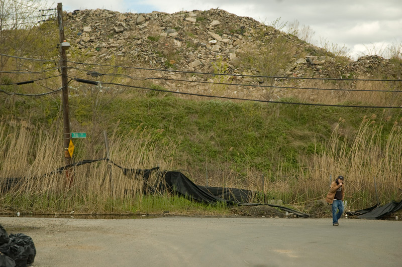 A man walk past a mountain of land fill.