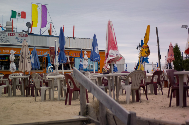 Empty outdoor tables with their umbrellas down.